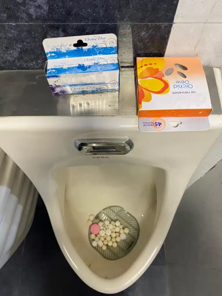 Urinal using Naphthalene Balls, Pink Urinal Cubes, Urinal Screens & Air Fresheners at the same time!
